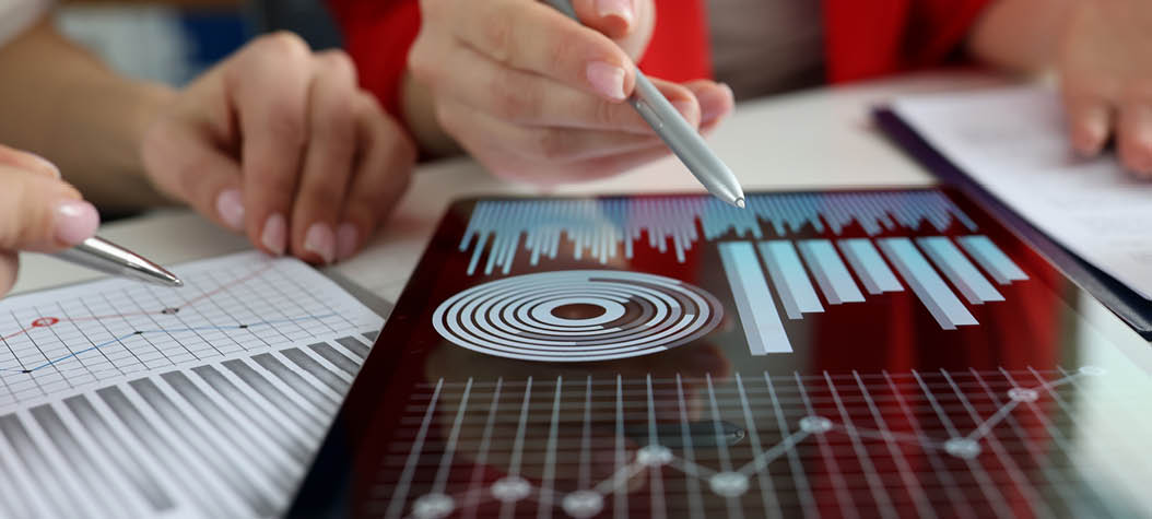 Business women studying charts and diagrams on digital tablet closeup  Business meetings concept